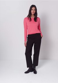Top ajustado de manga larga en rosa brillante, combinado con pantalones de pierna recta negros y botines negros brillantes. Textura suave, diseño minimalista.