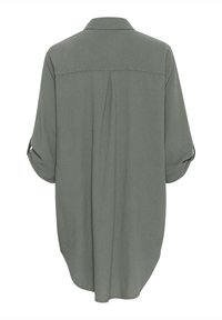 Camicia a maniche lunghe con bottoni in tessuto verde tenue. Presenta una piega sul retro, orlo rotondo e maniche con bottone per arrotolare. Tessuto morbido e leggero.