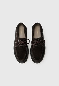 Scarpe in suede marrone scuro con lacci, caratterizzate da un design mocassino, dettagli in pelle e una suola cucita a contrasto.