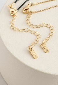 Halskette aus goldfarbenem Metall mit zwei rechteckigen Anhängern, die kleine klare Edelsteine enthalten. Umfasst eine Mischung aus ovalen Gliedern und einem strukturierten Akzent.