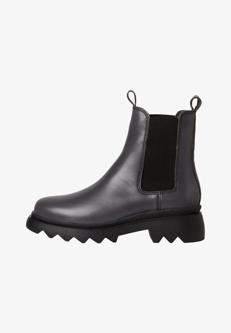 Black leather Chelsea boots with elastic side panels, chunky textured soles, and pull tabs for easy wear. Angular design with contrast accents.