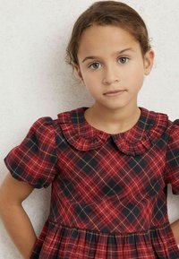 Röd och marinblå rutig klänning med korta puffärmar, volangkrage och upplagd kjol. Har fina gyllene linjer i mönstret.