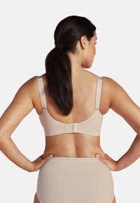 Beige-bh med justerbara axelremmar, texturerad band och hyskknäppning på baksidan, tillsammans med matchande högmidjade trosor.