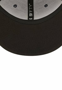 Cappello nero con visiera curva, logo metallico sotto la visiera e texture del tessuto visibile. L'interno presenta un rivestimento chiaro e fori di ventilazione.