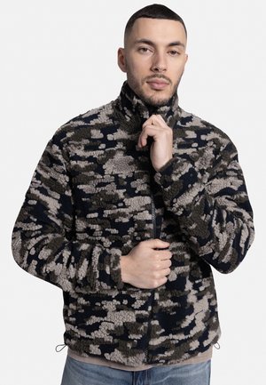 Fleece bunda v námornickém a béžovém maskáčovém vzoru, s vysokým límcem, zipem a volným střihem. Měkká, strukturovaná látka.