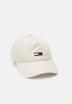 Gorra de béisbol color crema con visera curvada y pequeño logotipo rectangular en rojo, blanco y azul marino en el panel central frontal.