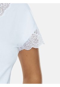 Biała bluzka na krótki rękaw z koronkowym wykończeniem przy rękawach. Materiał wydaje się miękki i gładki, z klasycznym okrągłym dekoltem.