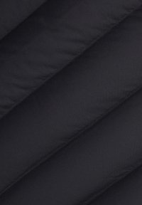 Svart puffjacka i tyg med diagonala quiltade paneler, slät textur och subtil lyster. Sömmarna är snyggt sydda för hållbarhet.