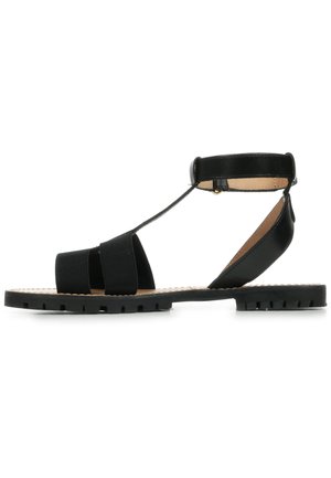 Sandalo nero con suola piatta, multiple cinghie elastiche per supporto e una cinghia alla caviglia con chiusura in metallo. Materiali in pelle liscia e gomma.