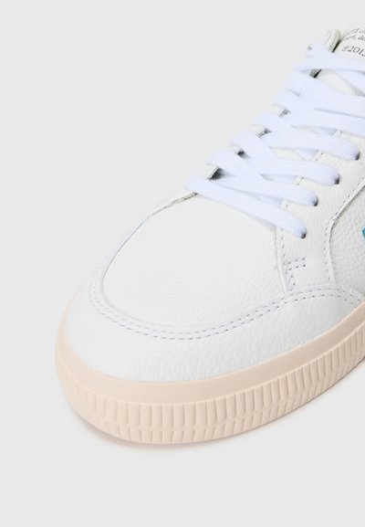 Witte leren sneaker met textuur bovenwerk, ronde neus, witte veters en lichtbeige rubberen zool. Verfraaid met subtiele blauwe logodetails.
