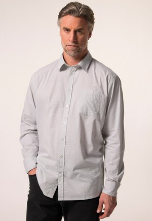 Camisa de botones gris claro con un pequeño patrón geométrico, de mangas largas, con un bolsillo en el pecho y un cuello clásico. Llevada sobre pantalones oscuros.