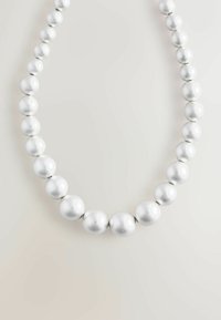 Srebrna ogrlica z biserji, ki vključuje okrogle, sijajne bisere različnih velikosti v graduiranem vzoru, ki prikazuje gladko teksturo in odbojno površino.