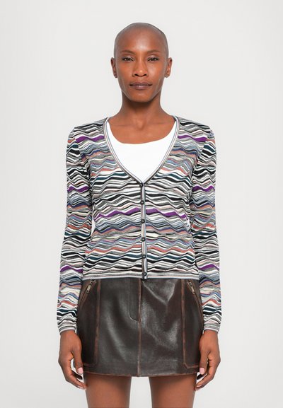 Cardigan multicolore avec motif ondulé, fabriqué en matériau doux, doté d'un col en V, de manches longues et d'une fermeture à boutons ; associé à une jupe en cuir marron.