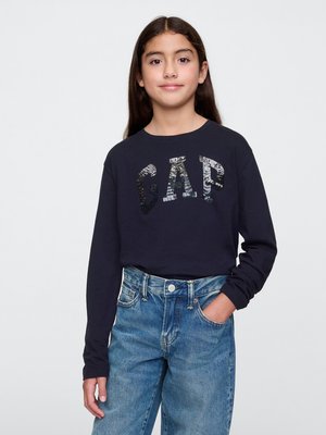 T-shirt a maniche lunghe blu navy con la scritta "CAP" in lettere di paillettes, abbinata a jeans in denim azzurro chiaro a vita alta con una vestibilità morbida.