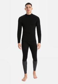 Fekete, hosszú ujjú hőszigetelő felső és fekete leggings, szürke díszítéssel az alsó lábszáron, rugalmas, könnyű anyagból készült.