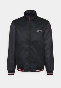 Giacca bomber nera con colletto alto, chiusura con zip, polsini e vita a costine con strisce rosse e bianche. Logo sul lato sinistro del petto.