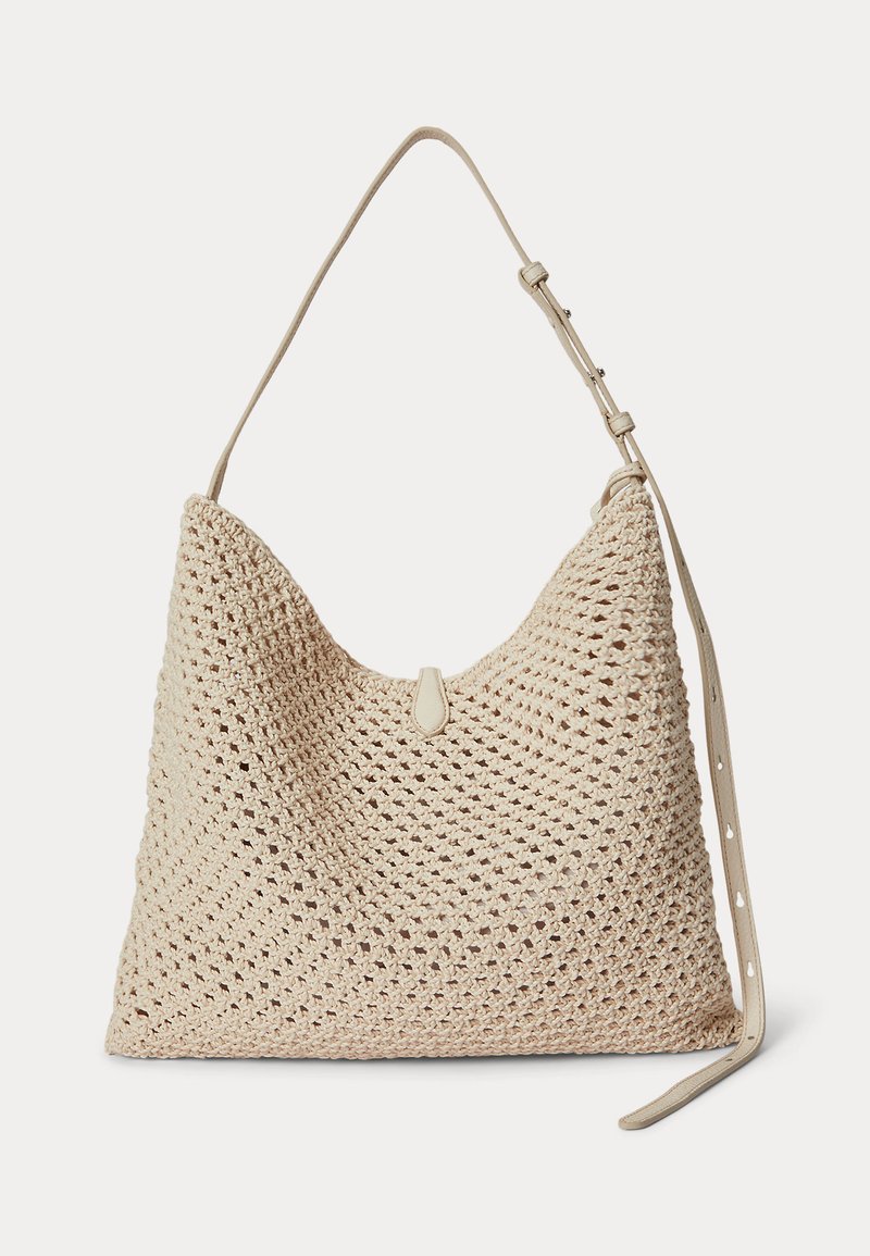 Sac d'épaule en paille tissée beige avec une bandoulière en cuir réglable et une petite languette en cuir pour la fermeture à l'avant.