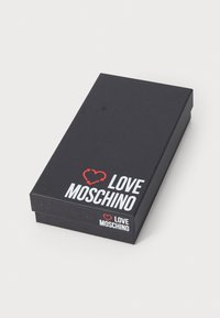 Caixa retangular preta com acabamento mate, apresentando a marcação "LOVE MOSCHINO" em vermelho e branco e um gráfico de coração na tampa.
