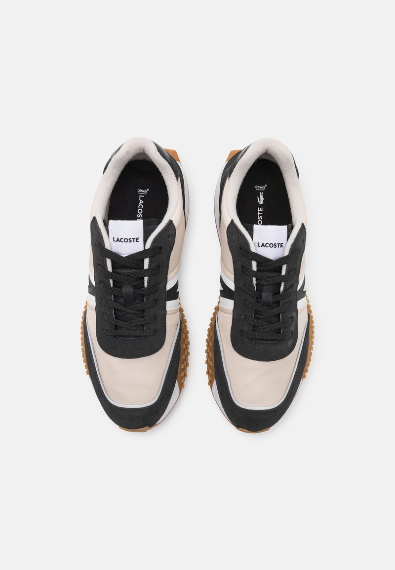 Baskets Lacoste présentant une combinaison de matériaux beige, noir et blanc, un design à laçage, une semelle en caoutchouc texturée et un dessus lisse.