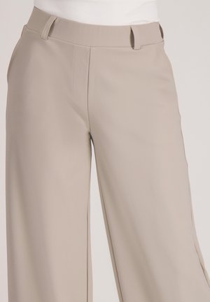 Beige wijde broek van gladde stof. Heeft een platte voorkant met riemlussen en een getailleerde pasvorm.
