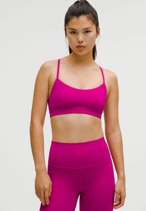 Fuksjowy stanik sportowy z cienkimi ramiączkami i poziomą taśmą, w połączeniu z dopasowanymi legginsami z wysokim stanem, wykonanymi z gładkiego, elastycznego materiału.