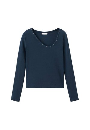Duži tamnoplavi top s dugim rukavima i V-izrezom, ukrašen ukrasnim srebrnim zakovicama uz rub izreza. Izrađen od glatkog, mekanog materijala.