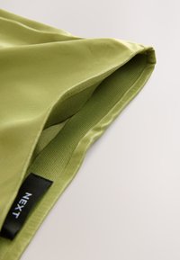 Olive green satin fabric with a smooth texture, featuring a slightly curved edge and interior lining in a matching shade. Tag visible.