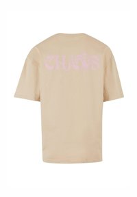 Beige Baumwoll-T-Shirt mit kurzen Ärmeln und einem grafischen Druck "CHAOS" in Pink auf dem Rücken, mit einem lockeren Schnitt und Rundhalsausschnitt.
