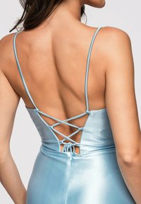 Femme portant une robe en satin bleu clair avec des fines bretelles et un dos ouvert lacé en croisillons.