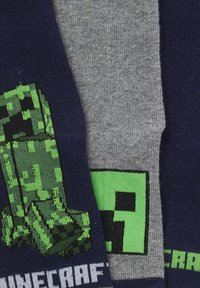Three pairs of socks: one navy with a green pixelated monster design, one gray with a green square pattern, and a navy pair with "Minecraft" text.