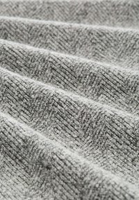 Tejido textil con un patrón de espiga, que presenta diferentes tonalidades de gris, transmitiendo una textura suave con sutil profundidad y dimensión.