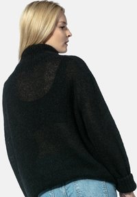 Czarny zdzierany sweter z wysokim kołnierzem, luźnym fasonem i teksturowanym wykończeniem. Posiada przezroczysty fragment na plecach oraz ribbowe mankiety.