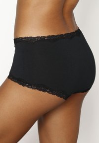 Mutande in cotone nere con pizzo ondulato, caratterizzate da un design a vita media e una texture liscia per il comfort.