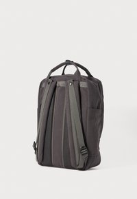 Grå tygryggsäck med vadderade remmar, handtag på toppen och sidfickor. Texturerade sektioner skapar en lagerdesign.