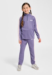 Paarse sportieve trainingspak met een ritssluiting bij de kraag en roze zijstrepen. De stof is glad, en de set bevat bijpassende broek en logodetails.