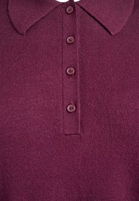 Polo de punto burdeos con cuello y cinco botones a juego, con una textura suave y costuras uniformes en toda la prenda.