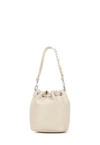 Sac seau en cuir beige avec un haut resserré, doté de clous décoratifs sur la bandoulière et de quincaillerie en ton argenté. Texture lisse, forme ronde.