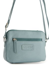 Hellblaue Leder-Umhängetasche mit Reißverschluss, Vordertasche und geprägtem Logo. Verstellbarer Riemen und weiche, strukturierte Oberfläche.