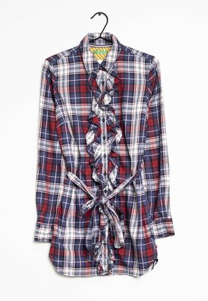 Camisa de cuadros de manga larga en azul marino, rojo y blanco. Presenta un frente con volantes, cierre de botones y un lazo en la cintura. Material de algodón con una textura suave.