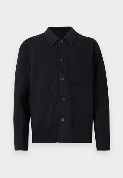 Μαύρο μακρυμάνικο πουκάμισο με κουμπιά, γιακά και μία τσέπη στο στήθος στην αριστερή πλευρά, εμφανίζεται πάνω σε ανοιχτό φόντο.