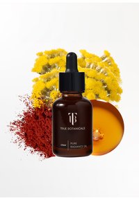 Mørk amber glasflaske med pipettehætte, mærket "Pure Radiance Oil," omgivet af gule blomster og rødt pulver på en hvid baggrund.
