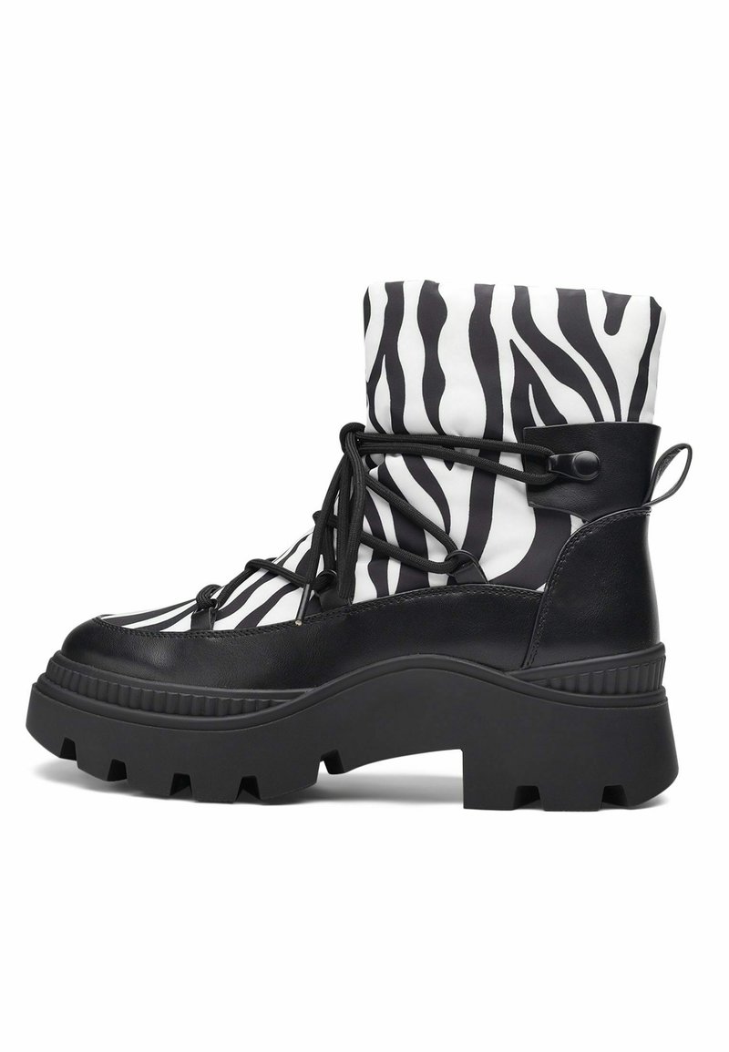 Botte plateforme noire avec semelle épaisse, lacets noirs et tige blanche ornée de larges rayures zèbre noires.
