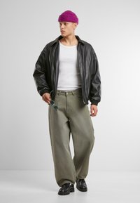 Black leather jacket over a white tank top, paired with wide olive-green pants. Accessories include teal sunglasses and a purple knit beanie.
