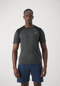 Black and grey athletic t-shirt with short sleeves, textured fabric, and a small logo on the chest; paired with blue shorts.