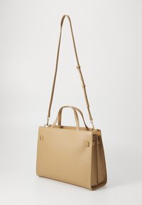 Sac à main structuré beige en cuir lisse, doté de deux poignées et d'une bandoulière amovible et réglable. Fermeture à rabat avec un matériel minimal.