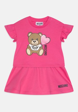 Abito t-shirt rosa con una grafica di un orso che tiene un palloncino a forma di cuore, con maniche a ruota e il marchio "MOSCHINO" in basso.