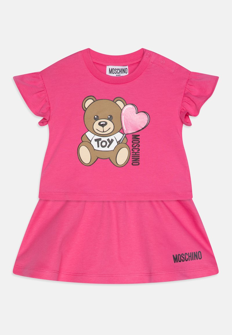 Vestido corto rosa con un gráfico de un oso sosteniendo un globo en forma de corazón, con mangas con volantes y la marca "MOSCHINO" en la parte inferior.
