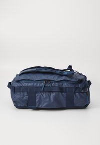 Tengerészkék sporttáska tartós anyagból, több cipzárral, masszív fogantyúkkal és webbing pántokkal a stabilitás érdekében.