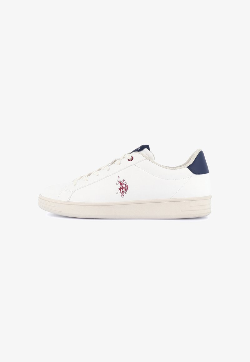 Baskets basses blanches avec lacets à l'avant, languette de talon bleu marine, semelle beige et petit logo rouge de joueur de polo sur le côté.