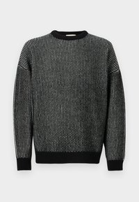 Maglione lavorato a maglia in bianco e nero con scollatura a girocollo, caratterizzato da un motivo testurizzato, polsini a costine e una vestibilità rilassata.